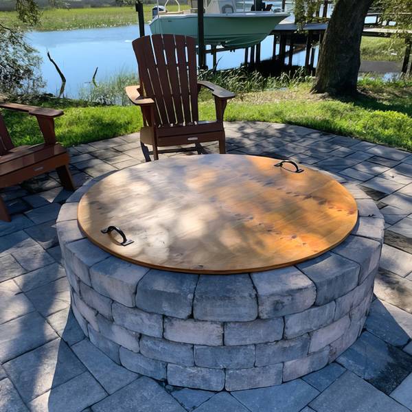 An outdoor conversation area complete with a fire pit with hand crafted wooden cover